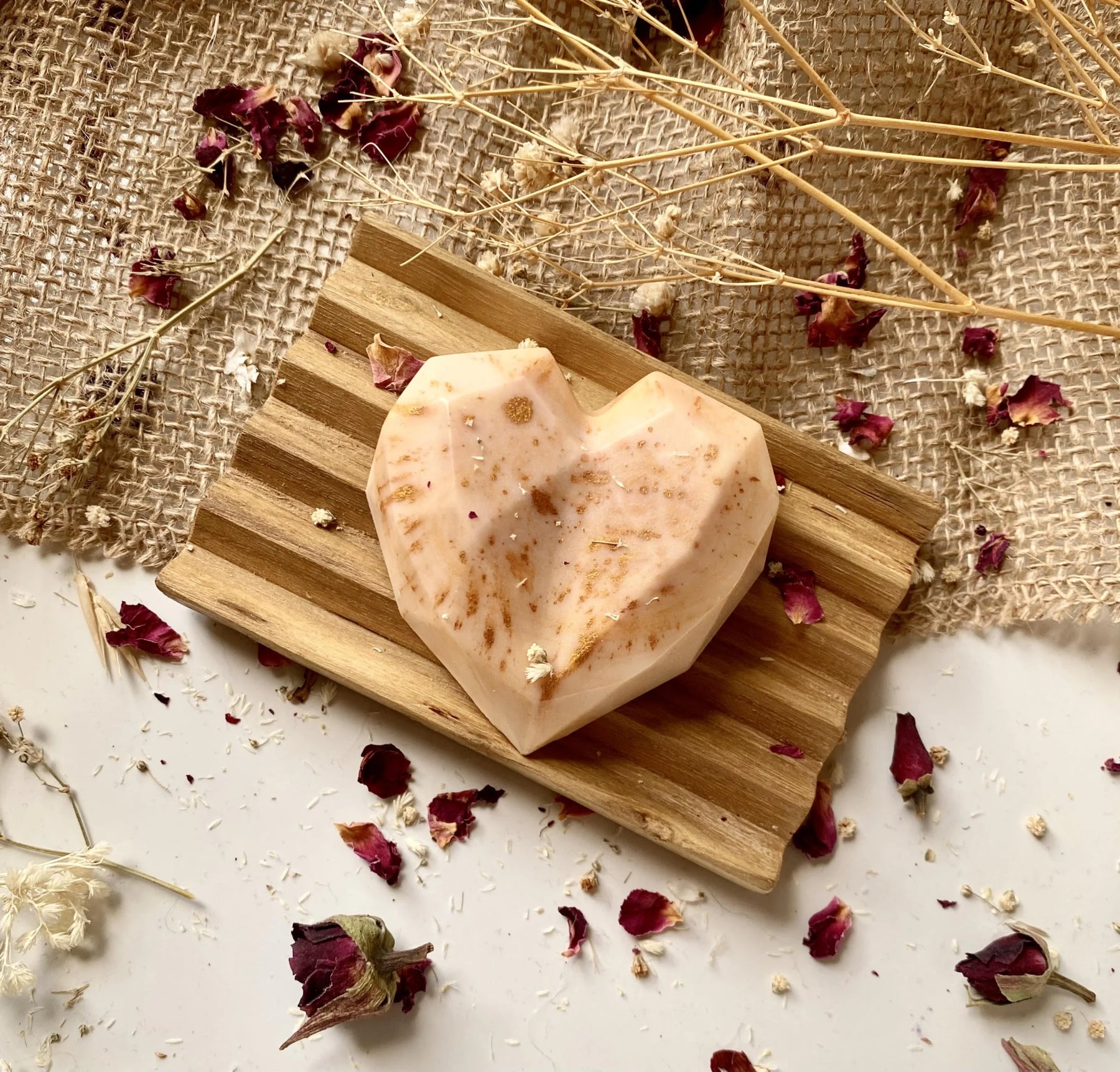 Ročno izdelano naravno milo v obliki srčka z osvežilnim vonjem limonske trave, nežno položeno na naravni podlagi.