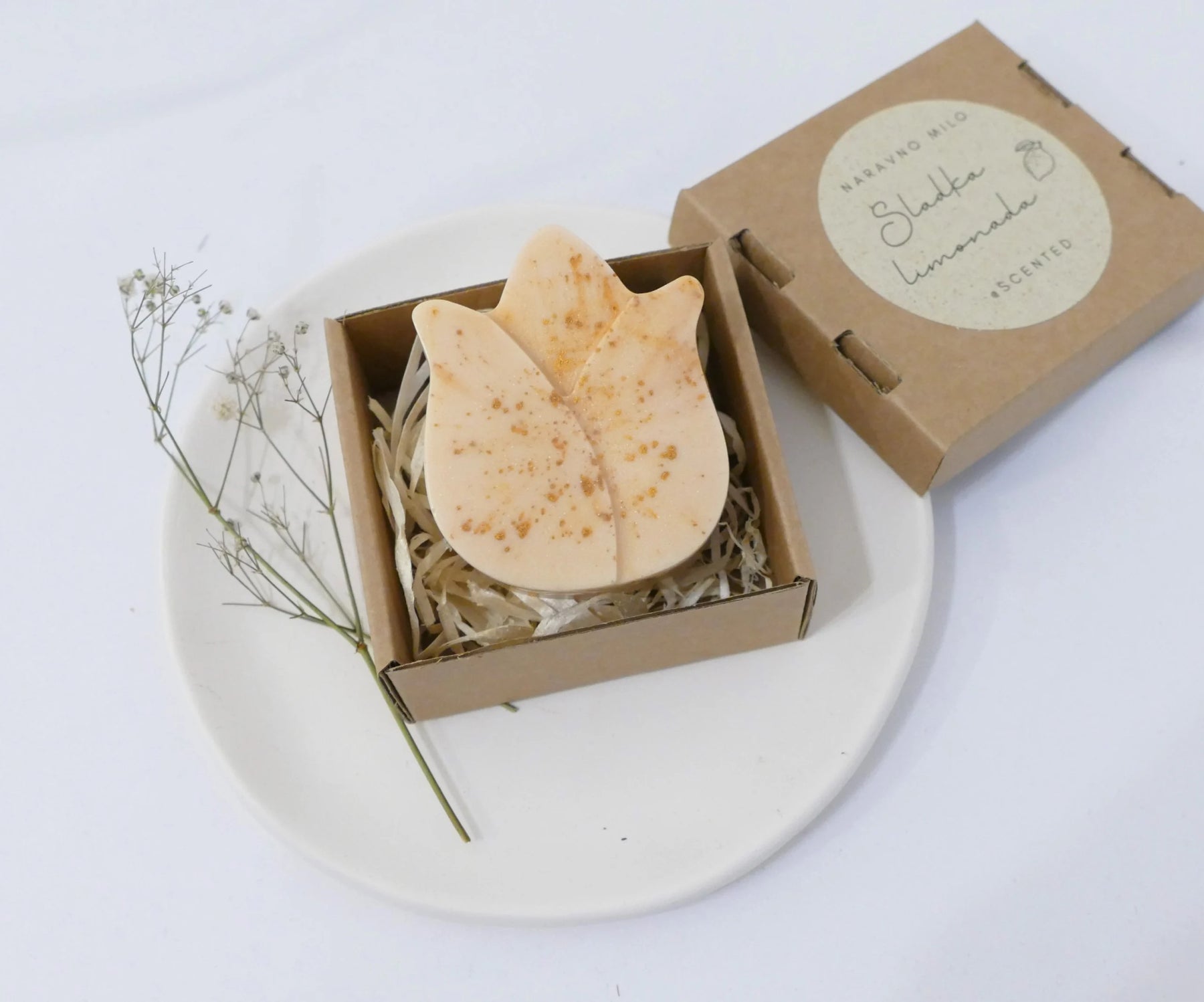 Ročno izdelano naravno milo z eteričnim oljem limonske trave v zlati barvi, elegantno zapakirano v škatlici.