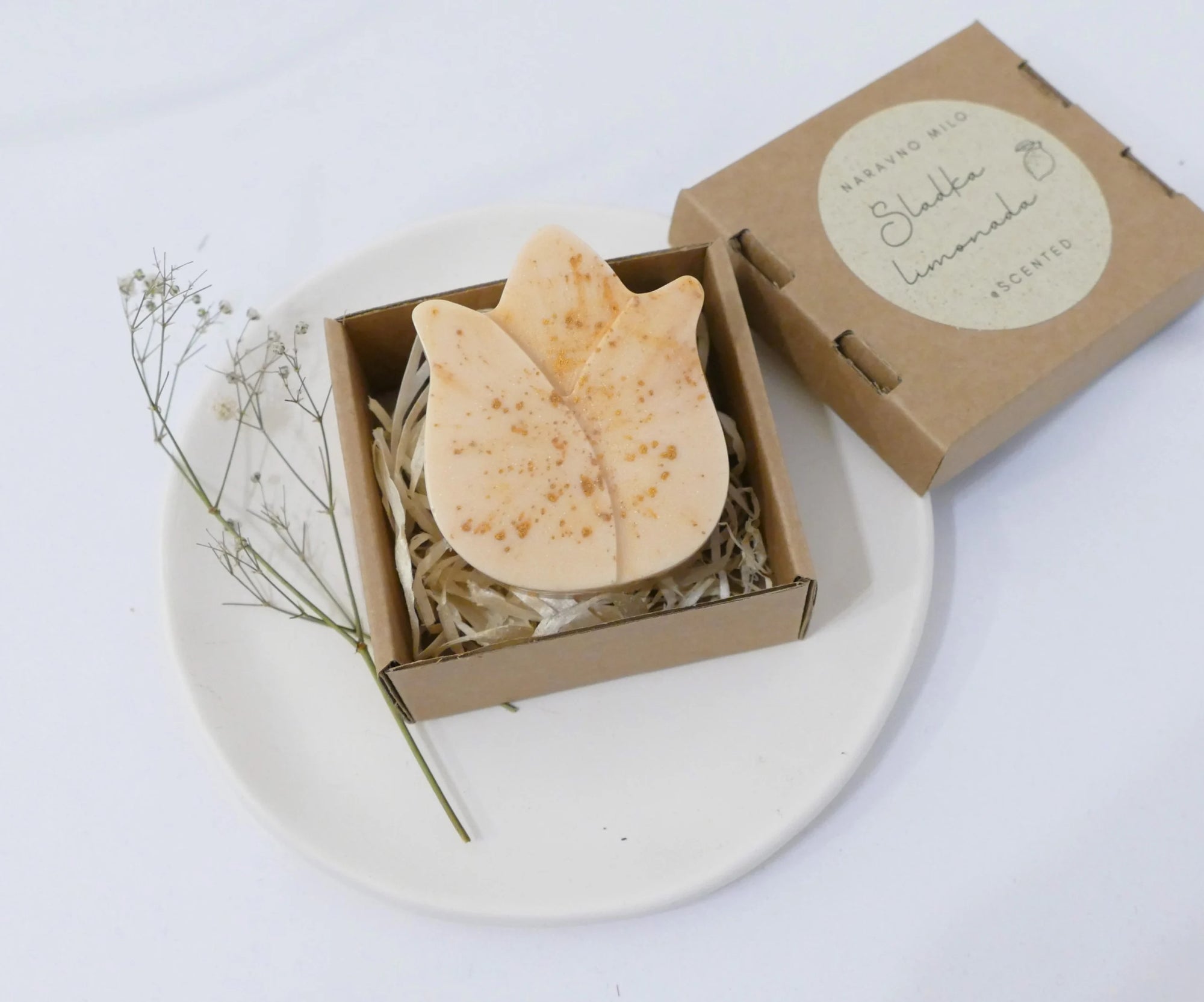 Ročno izdelano naravno milo z eteričnim oljem limonske trave v zlati barvi, elegantno zapakirano v škatlici.