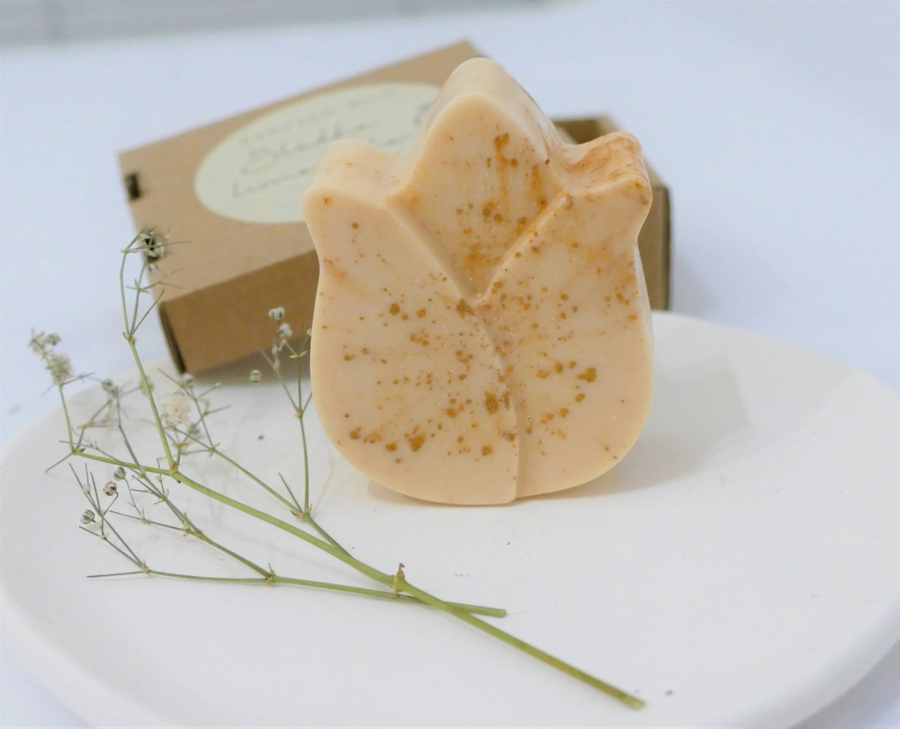 Ročno izdelano naravno milo z eteričnim oljem limonske trave v zlati barvi, elegantno zapakirano v škatlici.