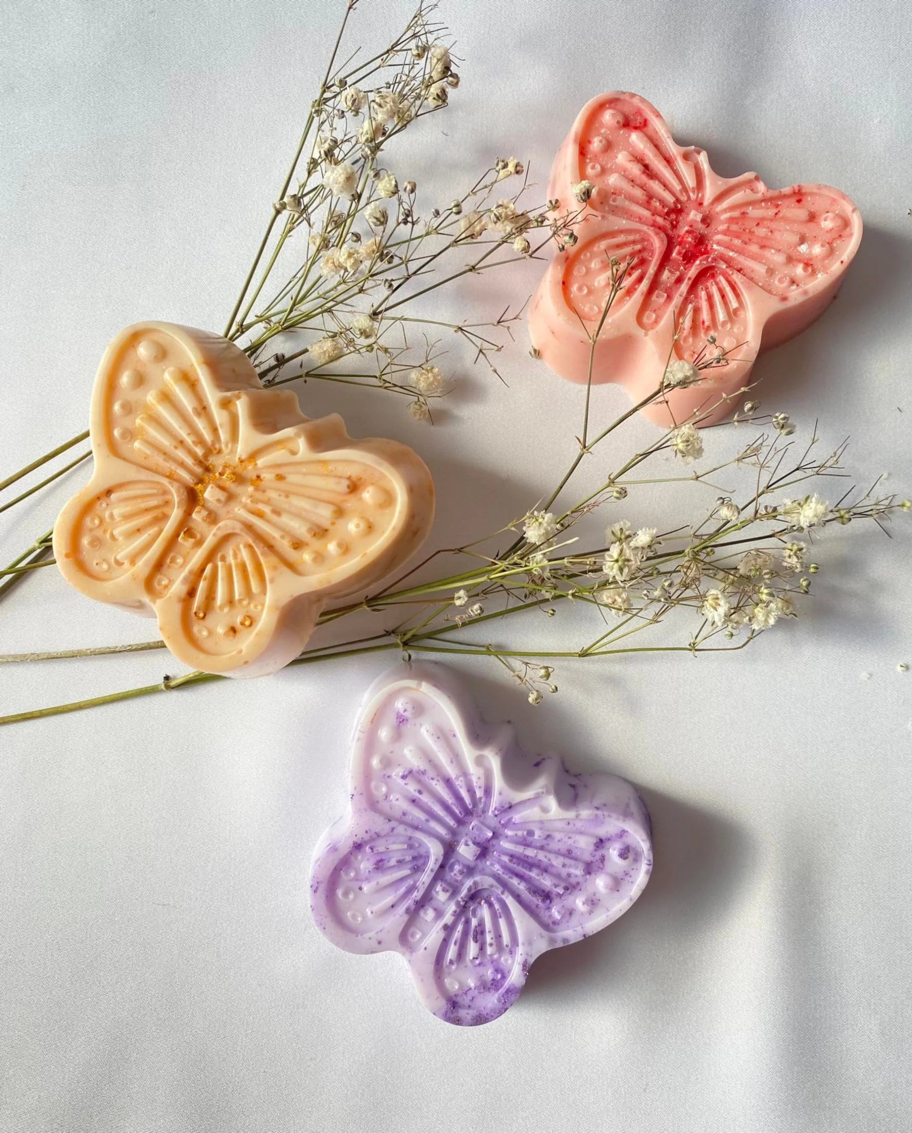 Naravno milo z eteričnim oljem sivke v obliki vijoličnega metulja – ročno izdelano, nežno in pomirjujoče, postavljeno na svetlo ozadje kot simbol sprostitve in naravne nege.