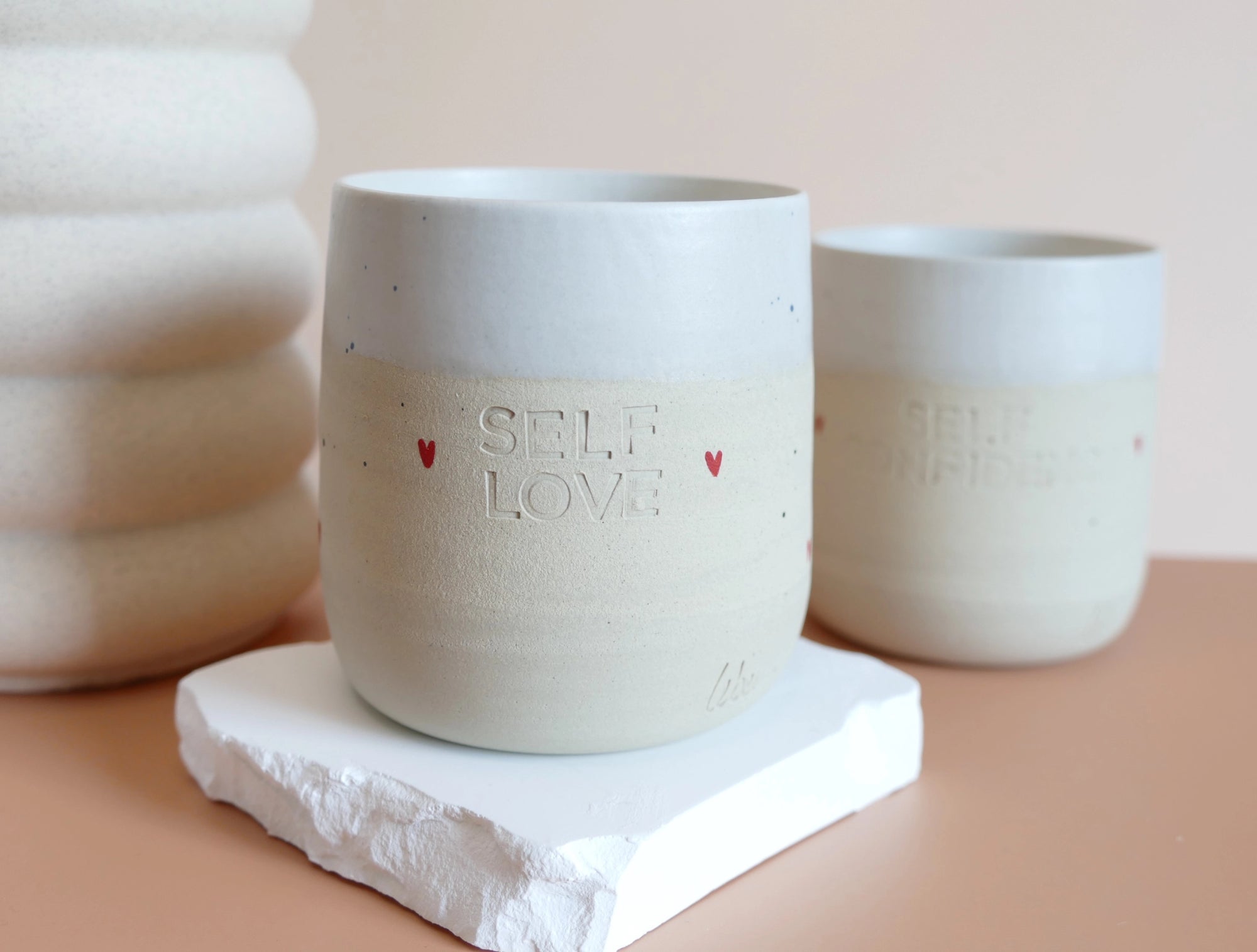 Unikatna dišeča sveča Self-love v ročno izdelani skodelici s sporočilom, obarvana v nežne tone – simbol ljubezni do sebe in trajnostnega razvajanja.