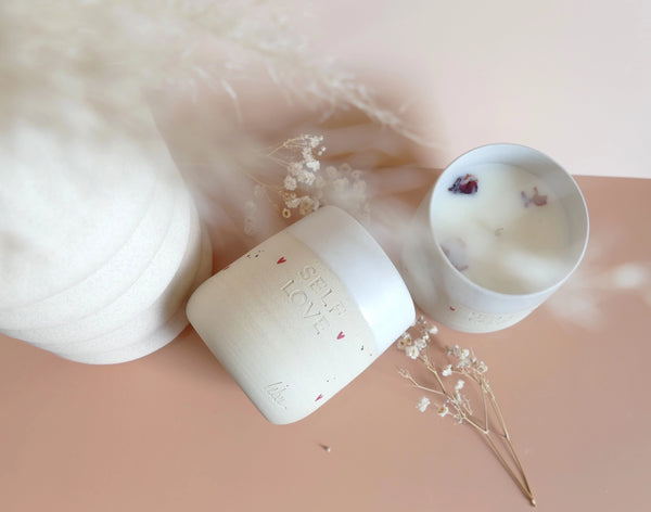 Unikatna dišeča sveča Self-love v ročno izdelani skodelici s sporočilom, obarvana v nežne tone – simbol ljubezni do sebe in trajnostnega razvajanja.