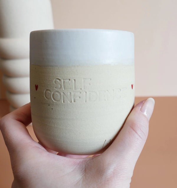 Ročno izdelana sveča Self Confidence v unikatni keramični skodelici z vtisnjenim napisom – združuje estetiko, aromaterapijo in pozitivno sporočilo.