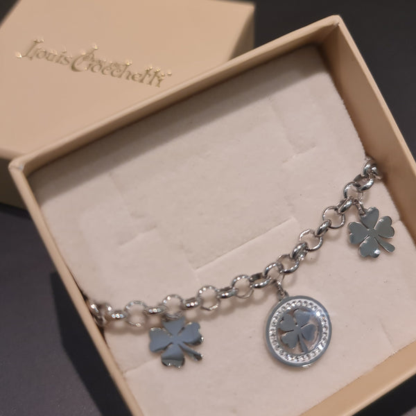 Pulsera de acero con cadena rolo que presenta 2 tréboles de cuatro hojas colgantes y 1 trébol central con piedras blancas