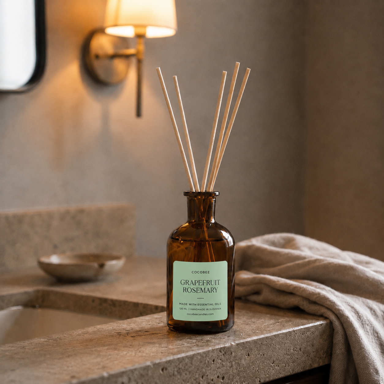 CocoBee Grapefruit Rosemary reed diffuser in an amber bottle on a bathroom counter