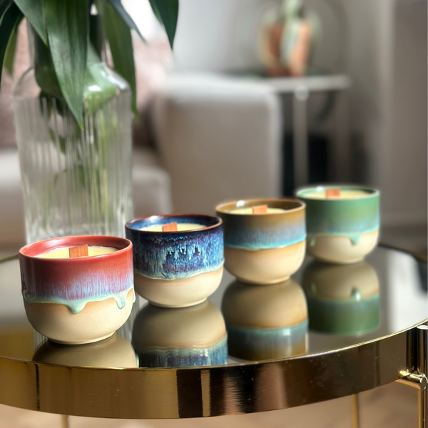 Set of colorful ceramic wood wick candles on a reflective surface with a blurred indoor background. Beeswax & Coconut Wax - CocoBee.