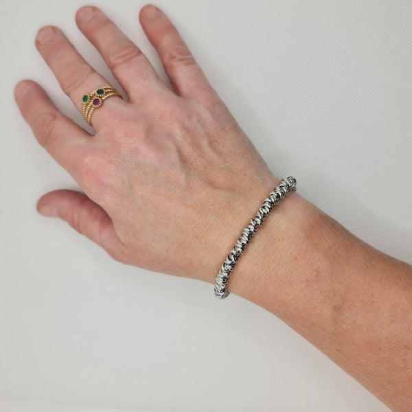 Shiny steel bracelet made of intertwined rings in the shape of knots