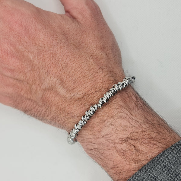 Shiny steel bracelet made of intertwined rings in the shape of knots