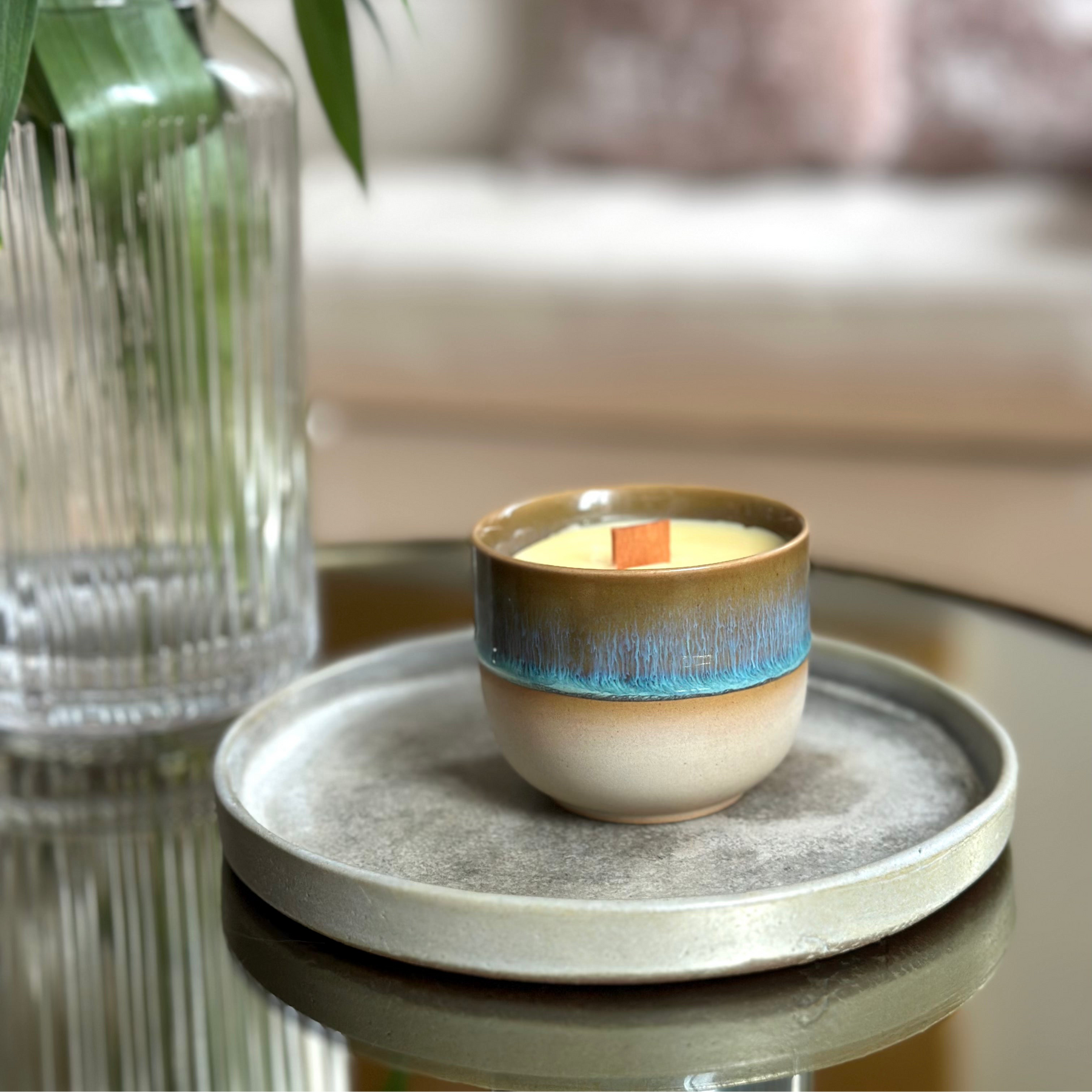 Ceramic wood wick candle with blue accent on a gray tray in a home setting. Beeswax & Coconut Wax - CocoBee.