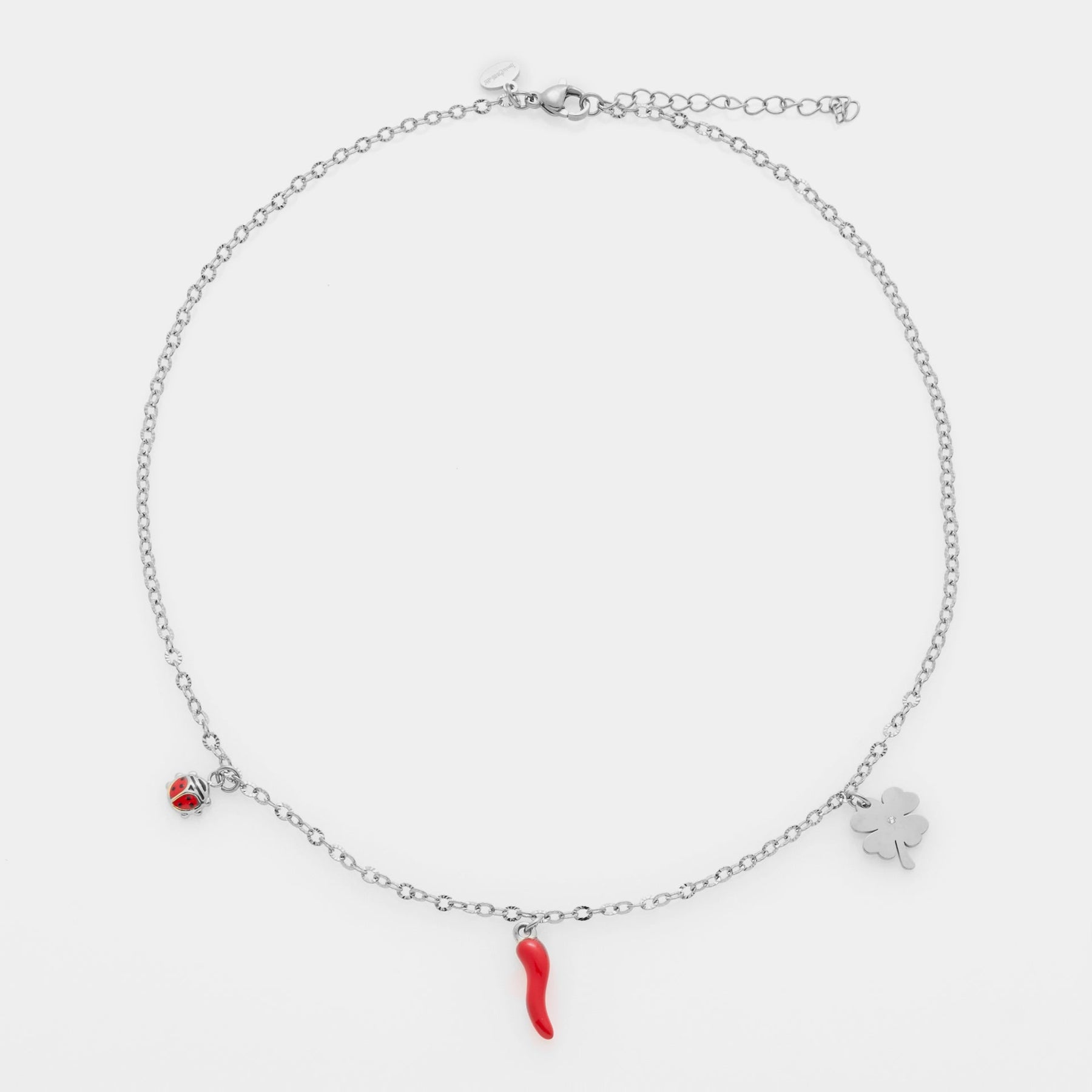 Fine steel necklace with rolò chain and three pendants: clover, red enamel horn, and red and black enamel ladybug