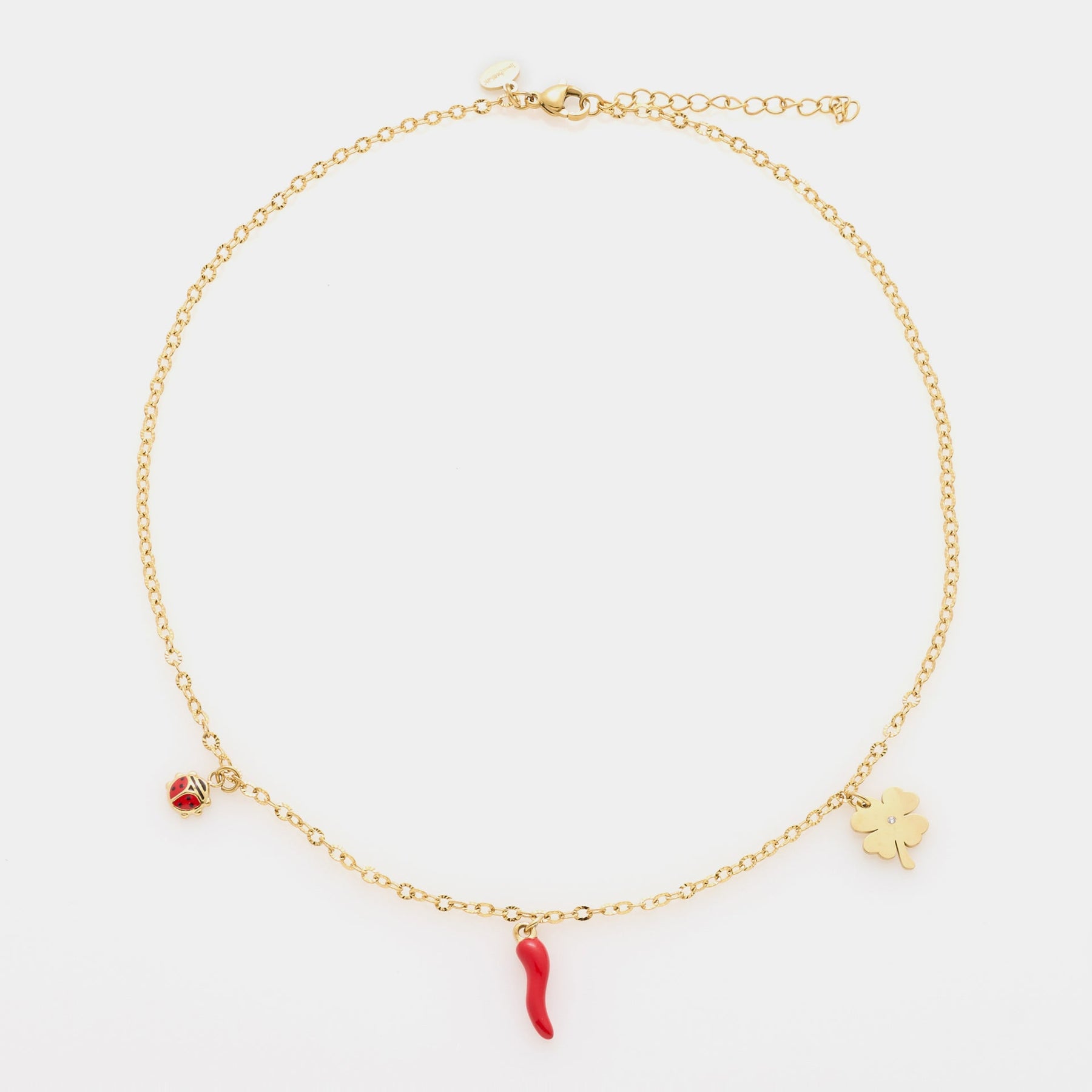 Pulsera de acero chapada en oro con cadena rolò fina y tres charms chapados en oro: trébol, cuerno y mariquita de esmalte rojo