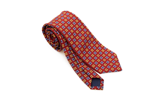 Cravatta a base rossa con motivo geometrico in pura lana