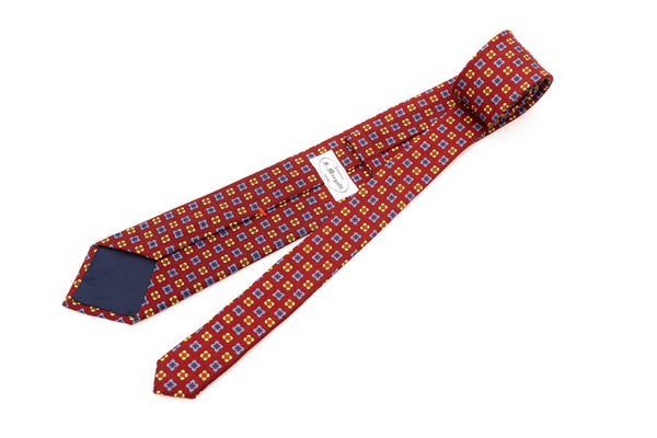 Cravatta a base rossa con motivo geometrico in pura lana