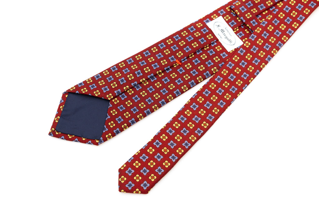 Cravatta a base rossa con motivo geometrico in pura lana