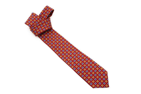 Cravatta a base rossa con motivo geometrico in pura lana