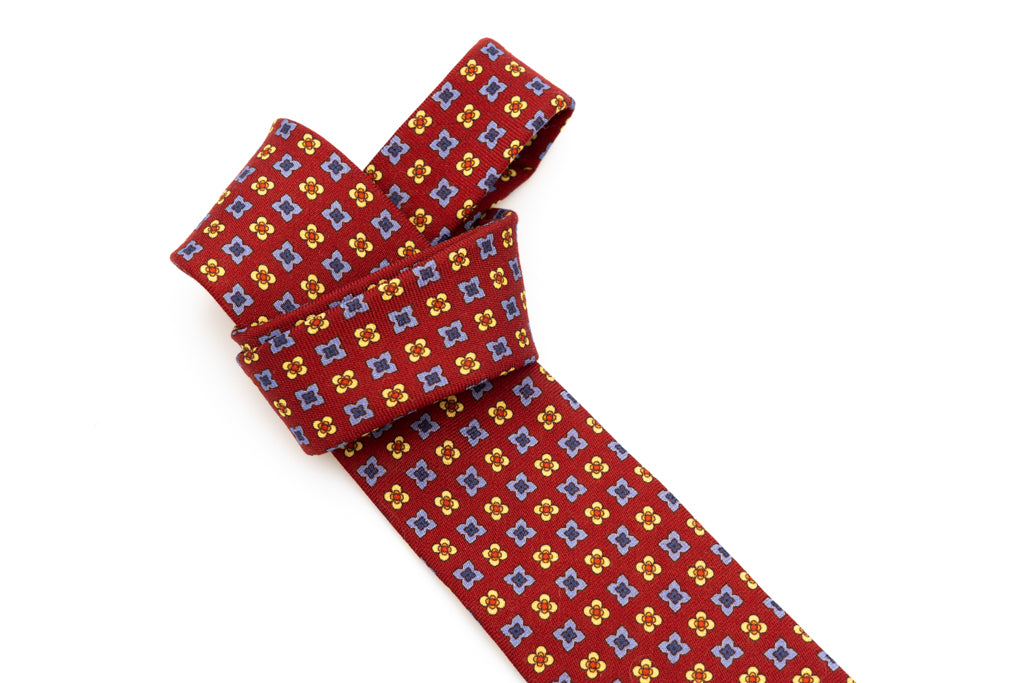 Cravatta a base rossa con motivo geometrico in pura lana