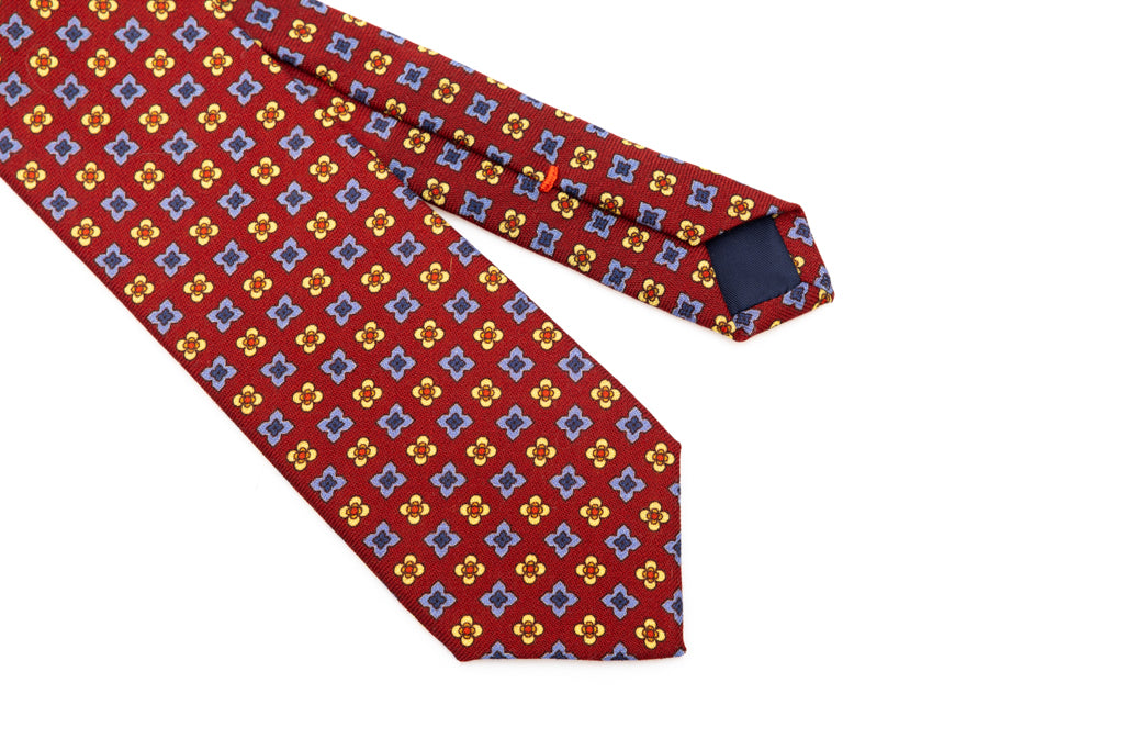Cravatta a base rossa con motivo geometrico in pura lana