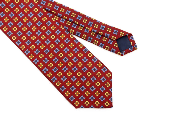 Cravatta a base rossa con motivo geometrico in pura lana
