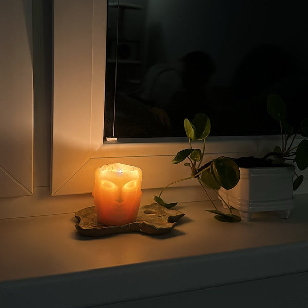Lit Inner Light sculptural candle on a windowsill