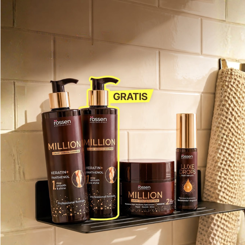 Hair care display on a shower shelf: two large Million keratin shampoo bottles with gold pumps, a Million mask jar, Luxe Drops serum bottle, and a towel nearby; yellow GRATIS tag in the background.