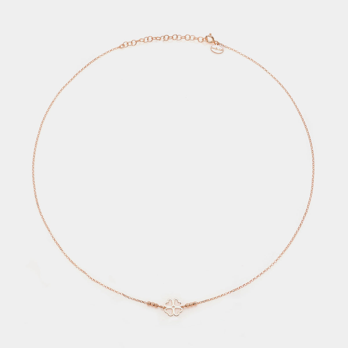 Rose gold silver necklace with clover centerpiece with heart-shaped pierced petals and 3 faceted spheres on the sides