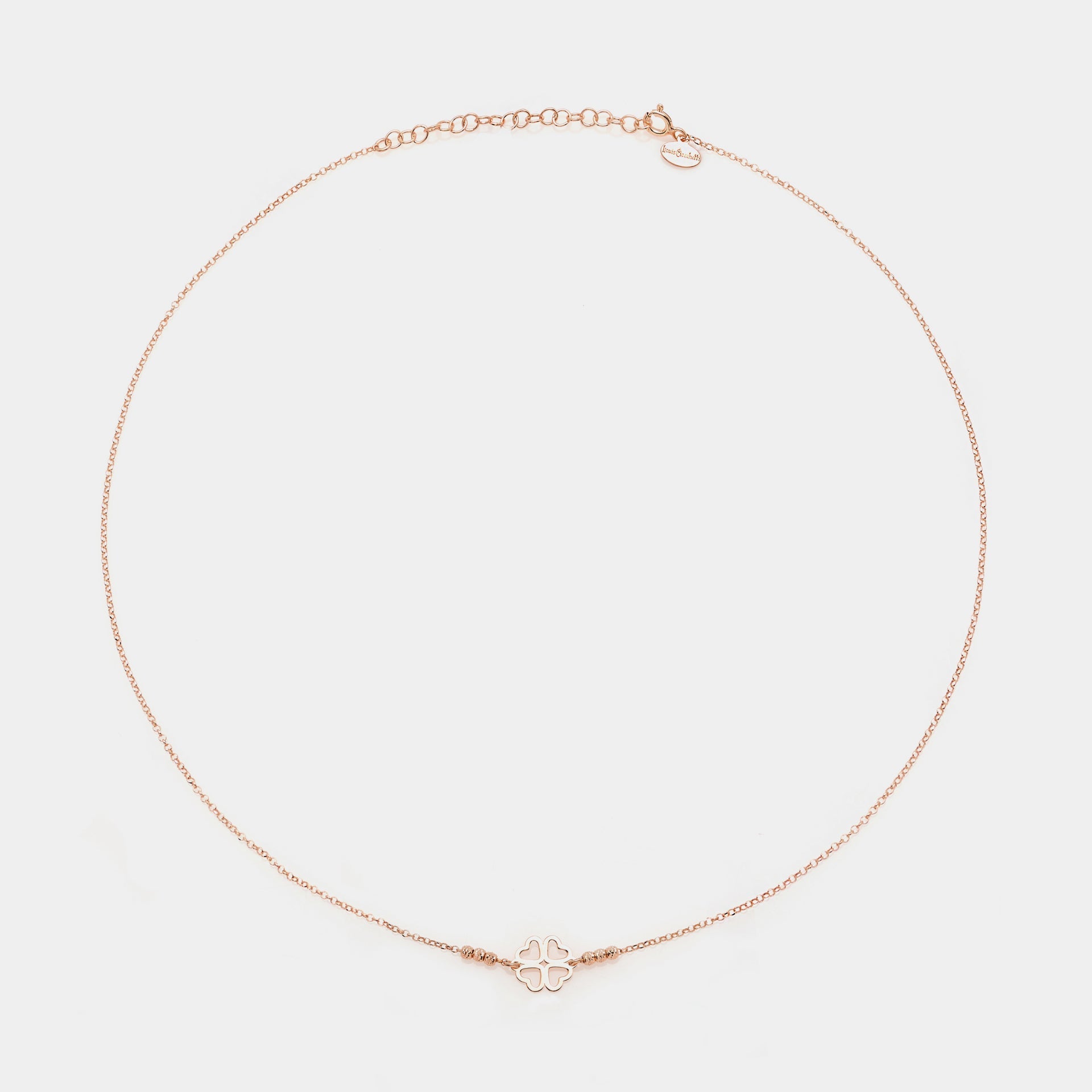 Rose gold silver necklace with clover centerpiece with heart-shaped pierced petals and 3 faceted spheres on the sides