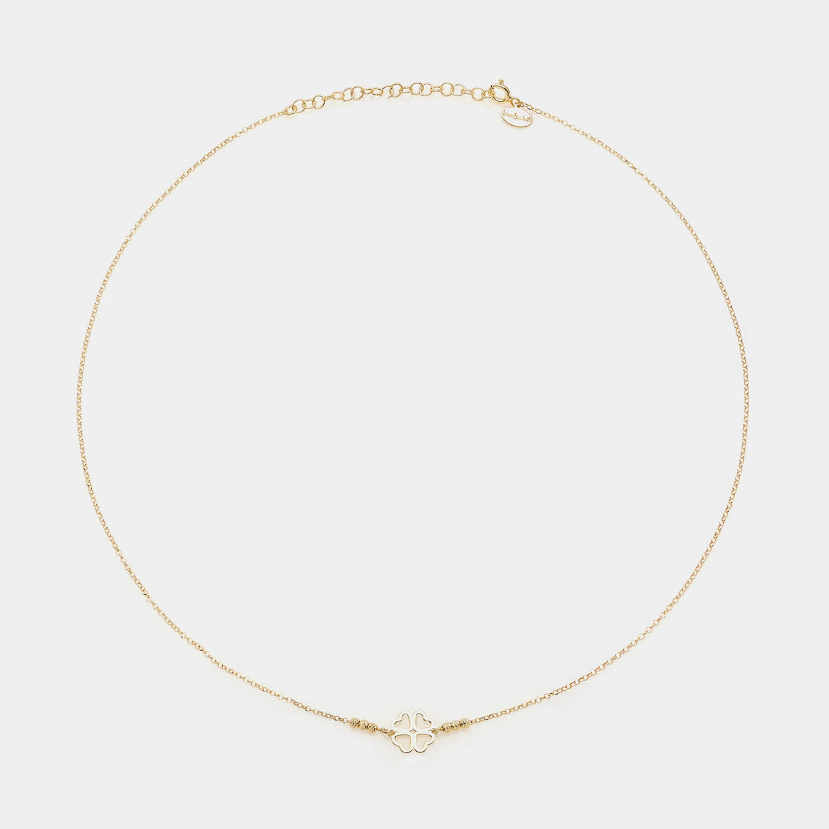 Gold-plated silver necklace with a central four-leaf clover with heart-shaped cutout petals and 3 faceted spheres on the sides