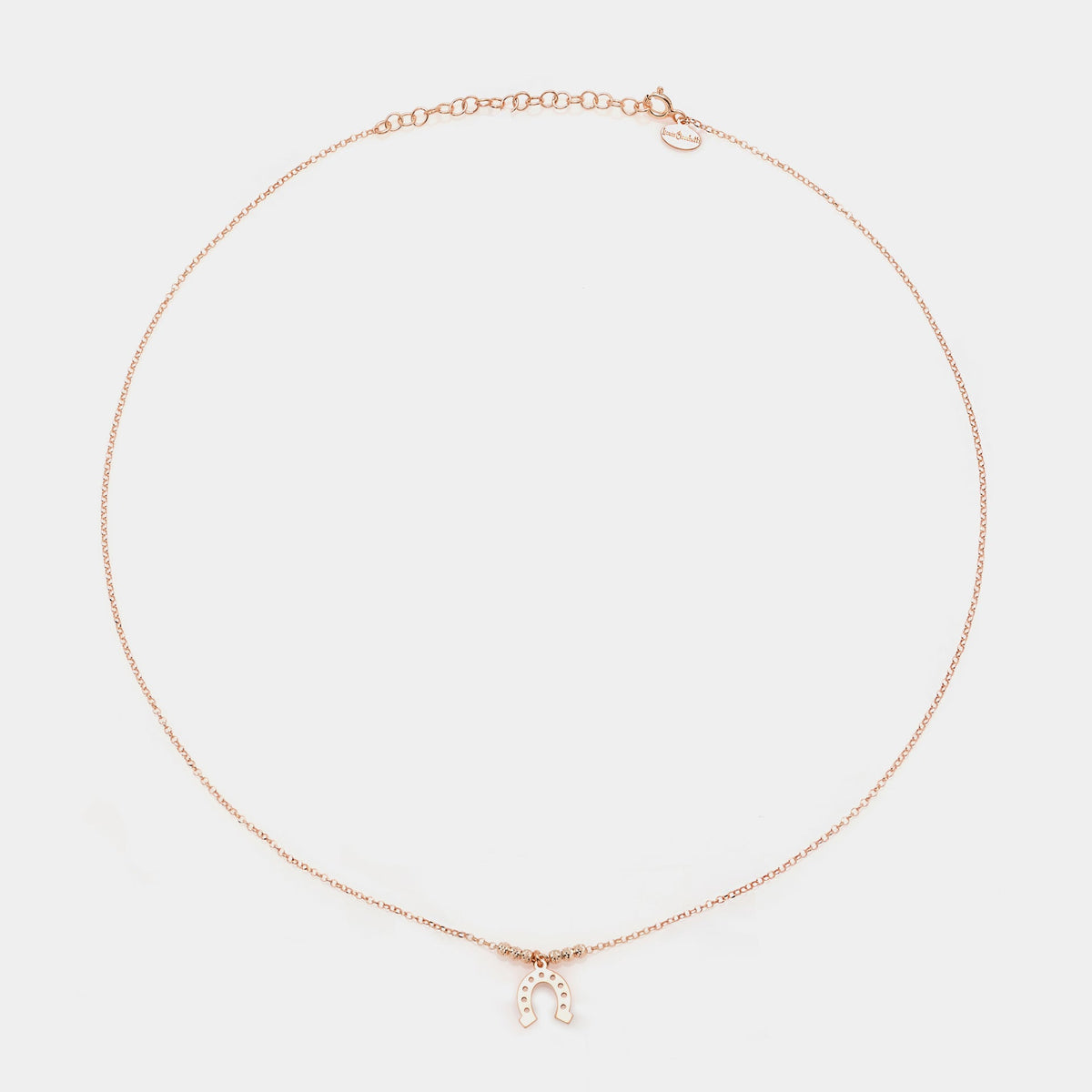 Rose gold silver necklace with a central hanging horseshoe and faceted spheres on the sides