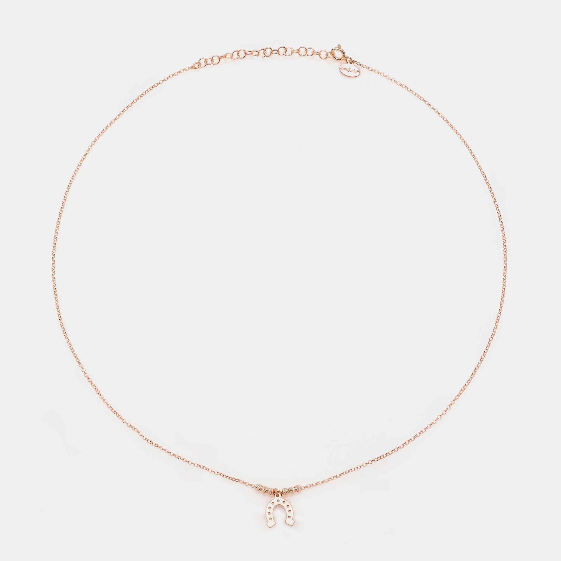 Rose gold silver necklace with a central hanging horseshoe and faceted spheres on the sides