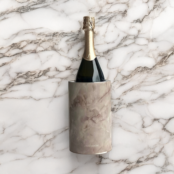 The Coolenator wine cooler marble onyx with a bottle of wine in it on a marble table.