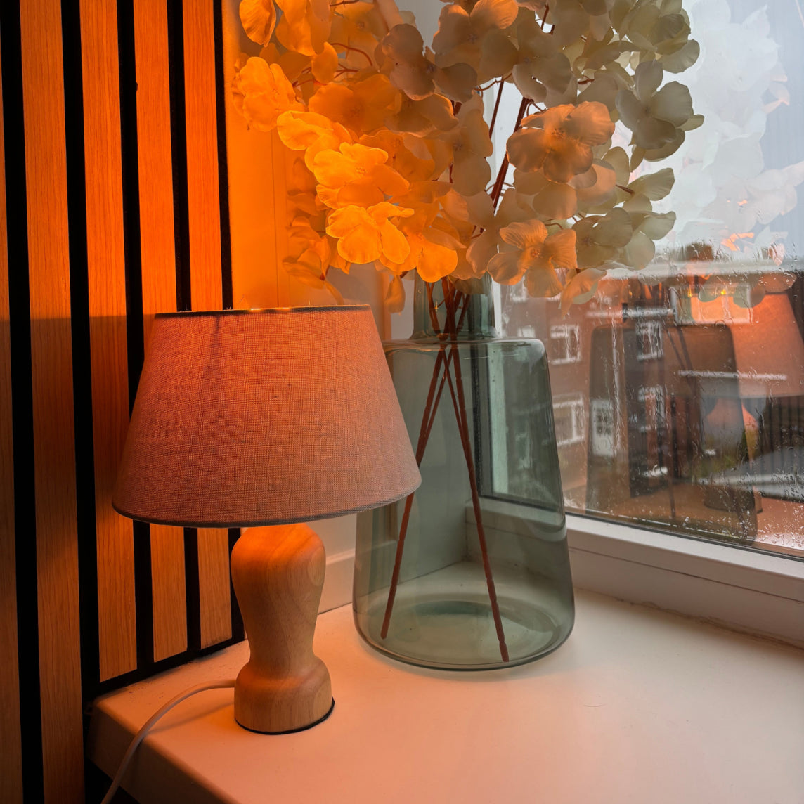 Japandi interieurstijl met een compacte houten lamp op een kastje bij een raam voor een rustige uitstraling.