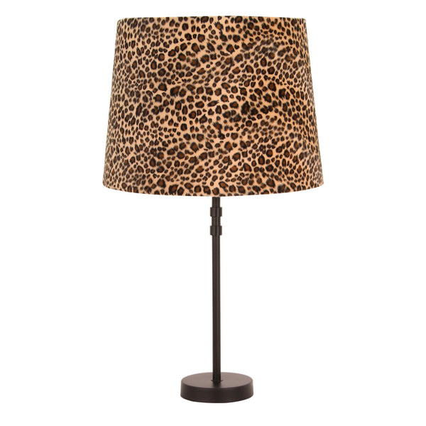 Sfeervol verlichte hoek met een zwarte lampvoet en een goudkleurige gloed door de panterprint kap.