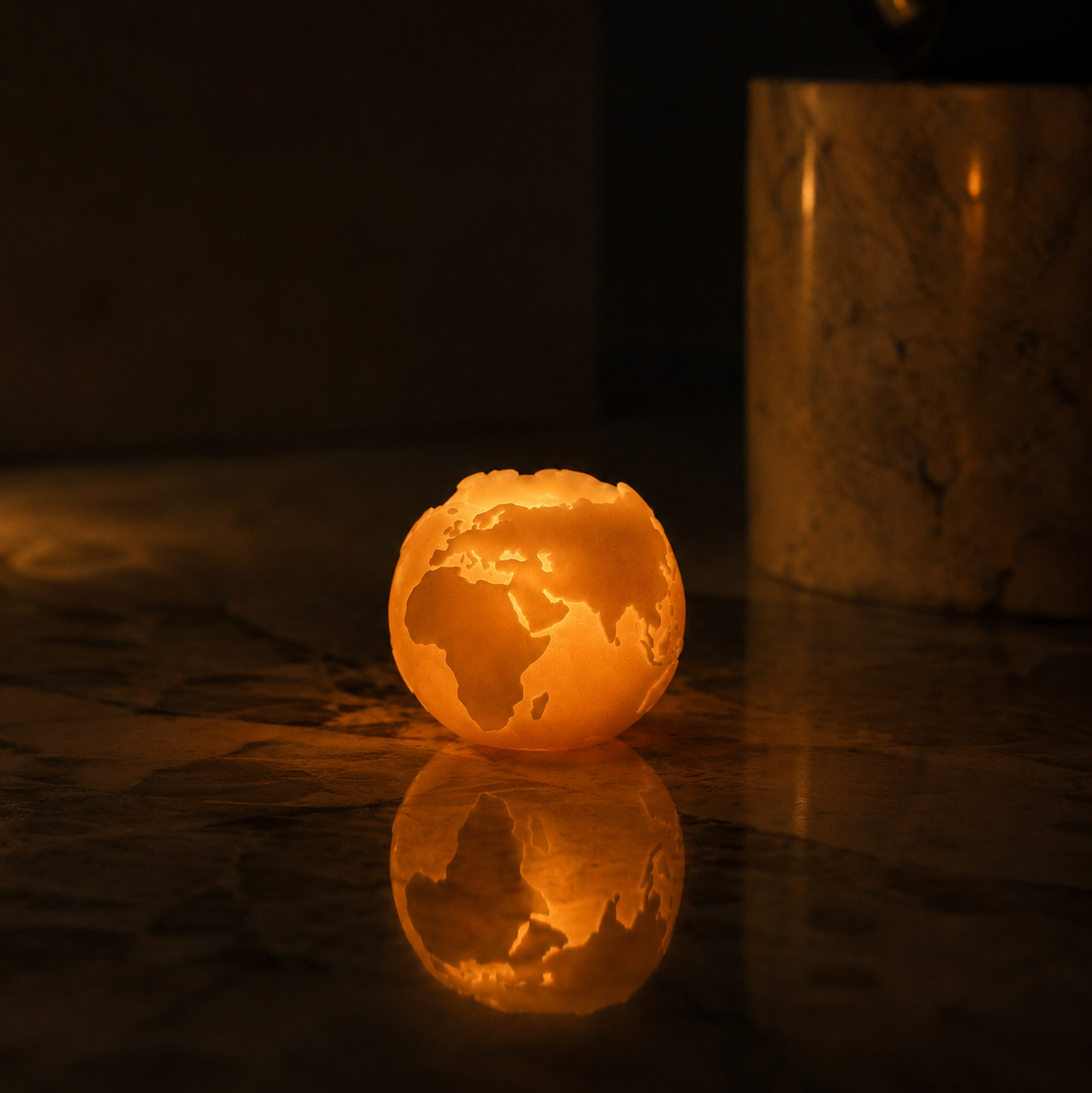 Globe-shaped CocoBee beeswax candle on a reflective surface