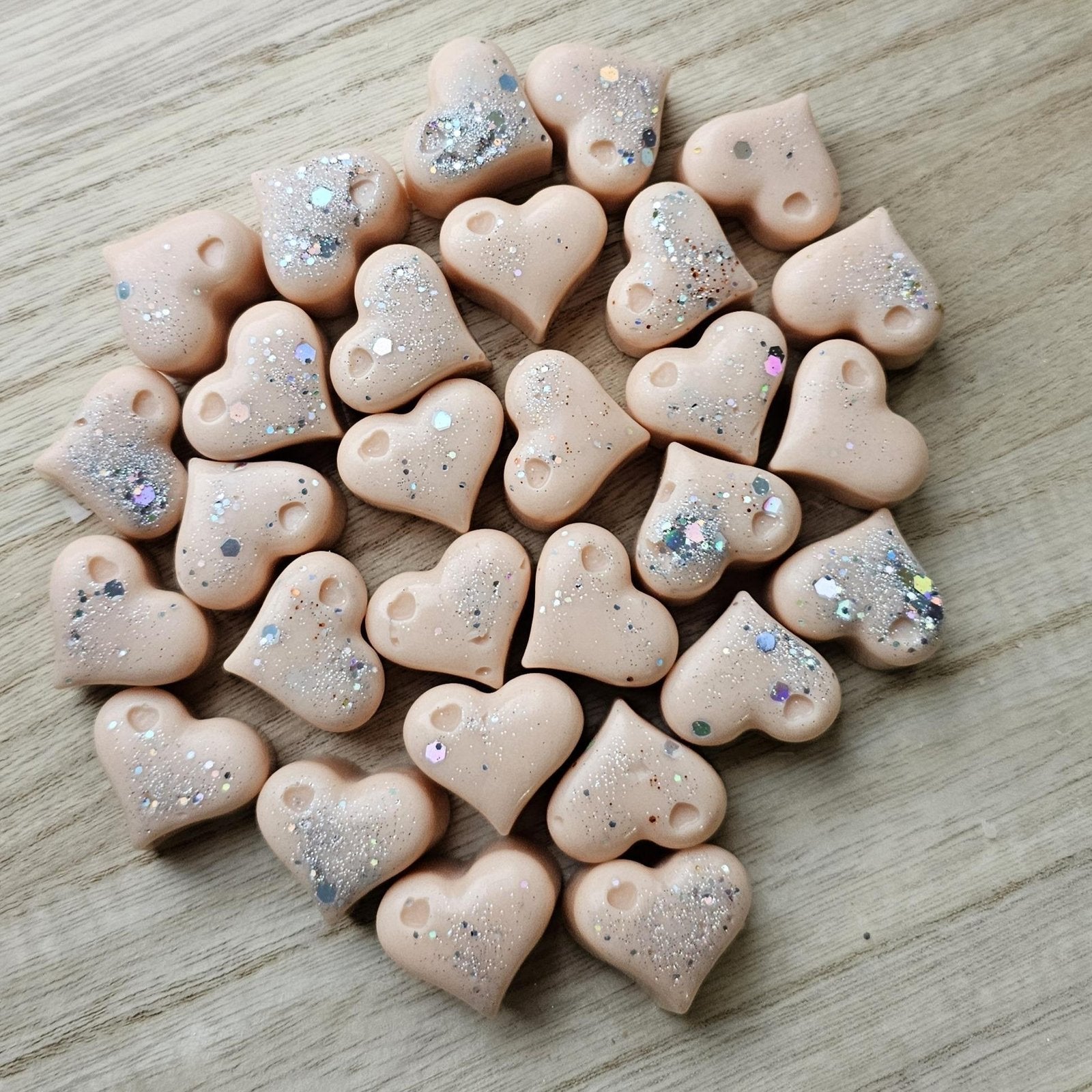 Ročno vliti srčki iz dišečega voska, fotografirani od blizu na mehki, svetli podlagi.