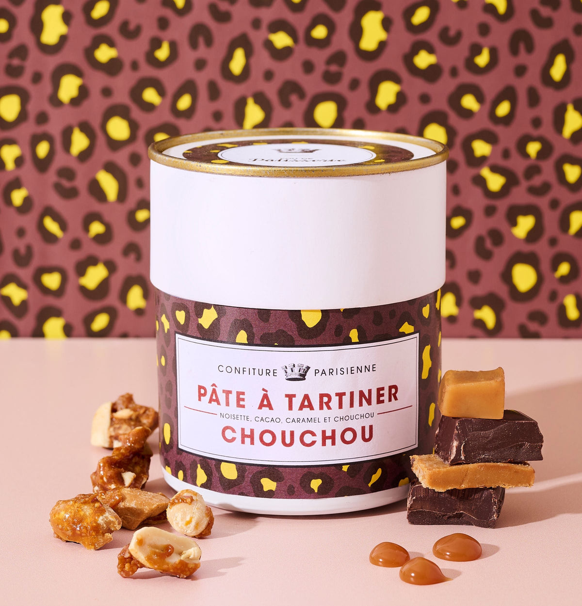 Pot de Pâte à tartiner Chouchou devant un fond léopard, entouré de cacahuètes caramélisées et de carrés de chocolat