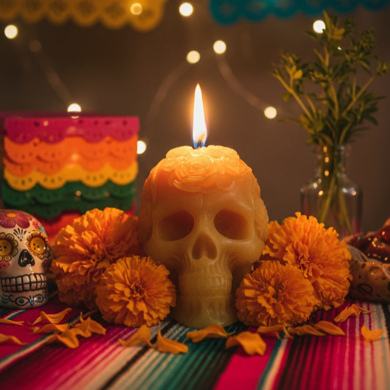 Skull-shaped candle with orange marigold flowers on a colorful tablecloth. Skull-shaped candle, día de muertos candle