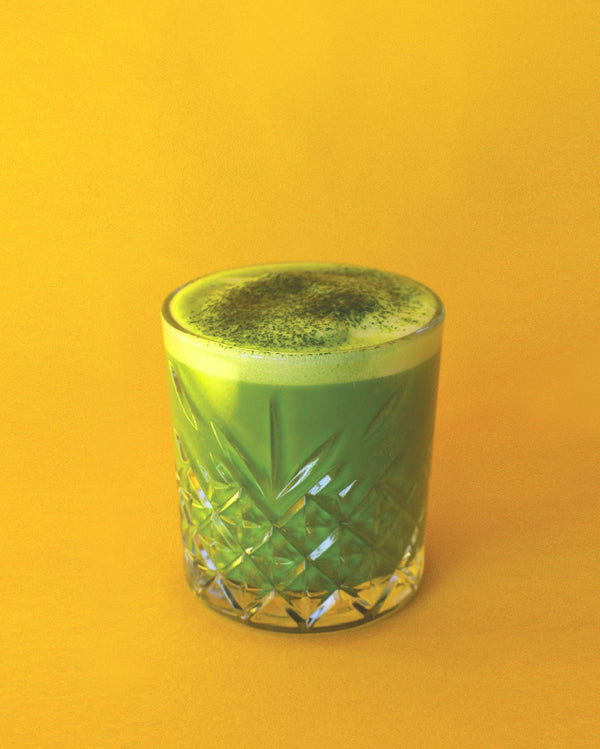 Matcha 7A whisked in a carved glass on a yellow background