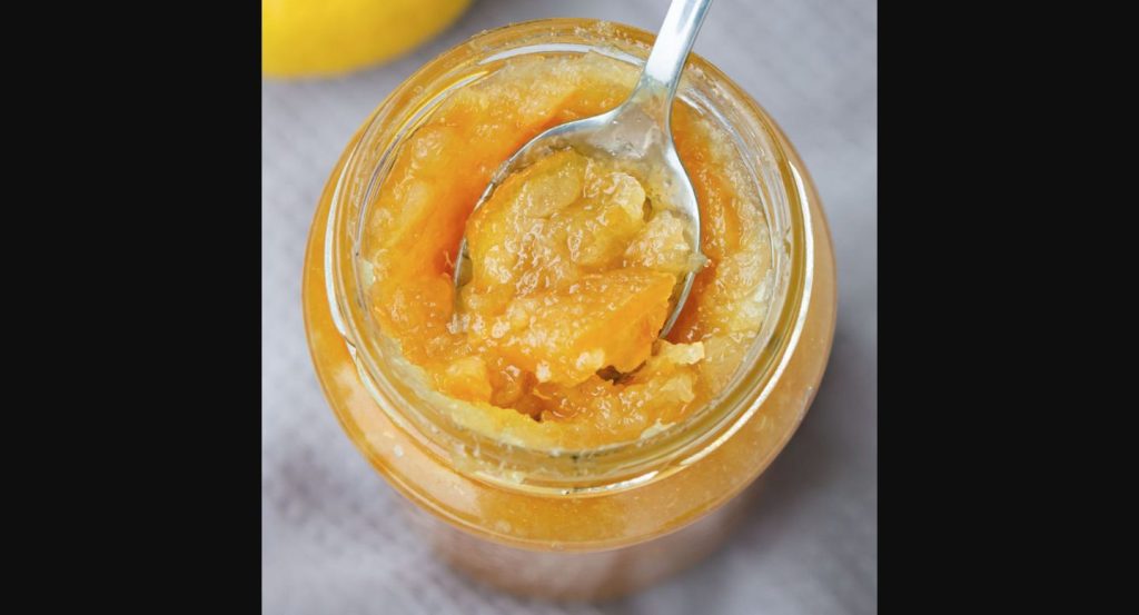 Izvirna fotografija odprtega kozarca limonine marmelade z žlico