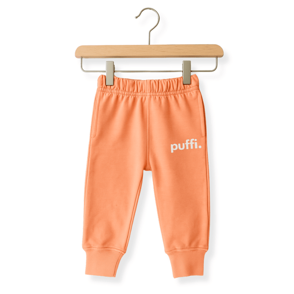 Deklica teče v otroških hlačah Puffi FUNDAY peach v parku