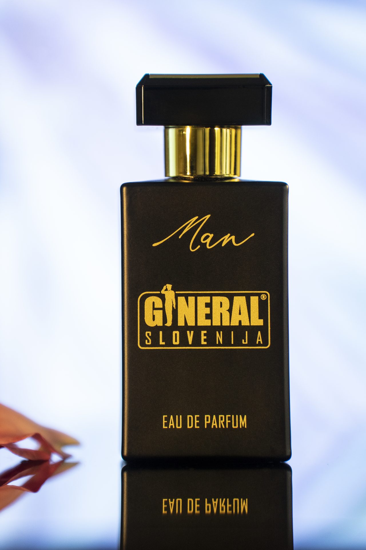 Close-up of a black rectangular perfume bottle with a gold cap and the word 'Man' in gold, brand General Ljubljana, Eau de Parfum image.