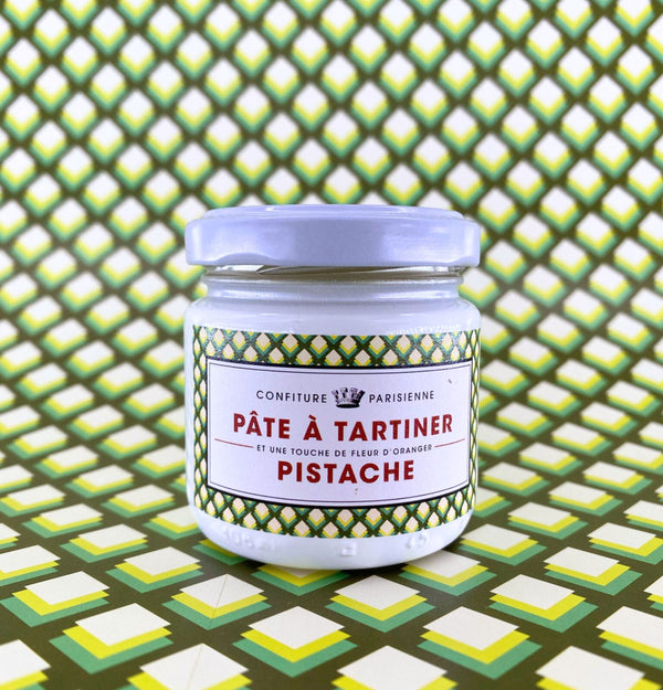 Pot de Pâte à Tartiner Pistache et fleur d'oranger posé sur un fond graphique à motif d'écailles vert et jaune