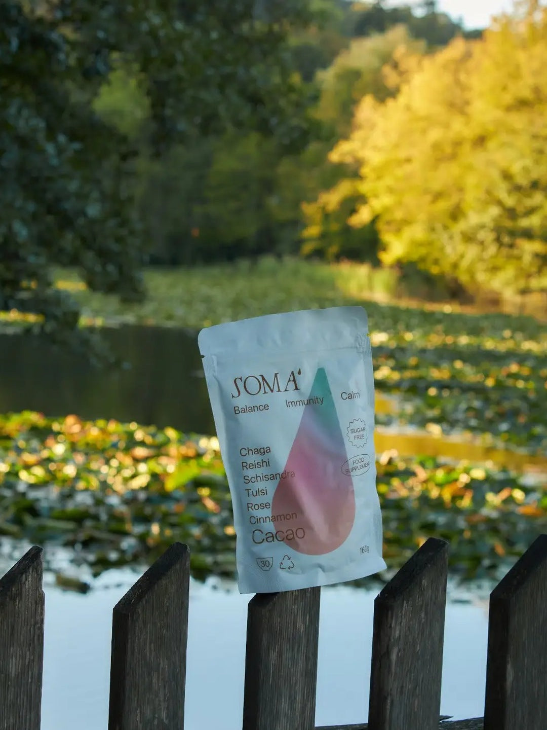 Soma Cacao Balance pouch on a wooden fence by a lily pond in autumn